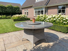 Rio Ronde Tuintafel 130 cm - Glas / Light Kobo Grey in een sfeervolle tuin - Outnest tuinmeubelen